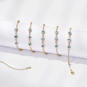 Détail macro de chaînes de ventre en or 14K avec pendentifs en émail bleu de mauvais œil