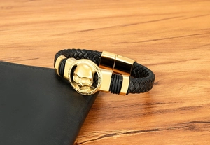 Dettaglio di un bracciale da uomo in pelle nera con teschio dorato e chiusura magnetica