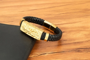 Nahaufnahme der Goldplatte mit Götter-Relief und geflochtenem Leder am Herrenarmband