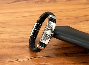 Dettaglio di bracciale in pelle nera intrecciata con placca teschio in metallo e chiusura magnetica