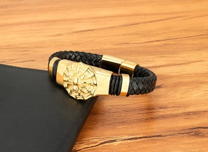 Détail de bracelet en cuir pour homme avec plaque araignée dorée et fermoir magnétique