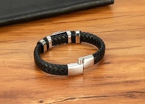 Détail d'un bracelet en cuir tressé noir avec fermoir en acier sur surface en bois
