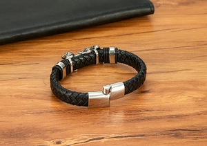 Nahaufnahme von schwarzem Lederarmband mit silbernem Drachenverschluss auf Holz