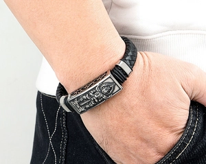 Detail eines Herren-Lederarmbands mit gravierter religiöser Buddha-Metallplatte am Handgelenk