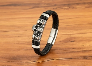 Detail of multi-strand braided leather bracelet with three carved silver skulls and magnetic clasp