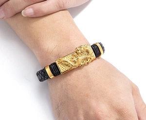 Nahaufnahme des Herren-Lederarmbands mit goldener Drachenprägung und geflochtener Optik