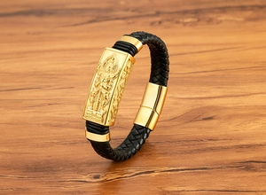 Detail eines schwarzen Lederarmbands mit goldener Buddha-Relief und Magnetverschluss