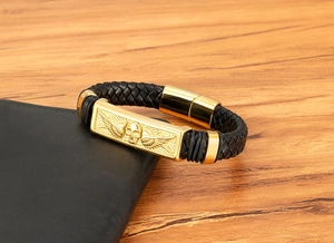Close-up of gold skull wing emblem and braided leather on punk men's bracelet