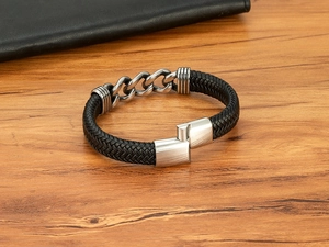Nahaufnahme eines Herren-Lederarmbands mit geflochtener Schnur und silbernen Gliederketten