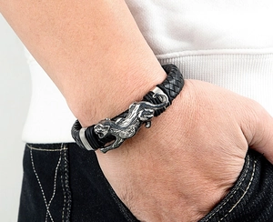Nahaufnahme eines schwarzen Lederarmbands für Herren mit silbernem Panther-Anhänger