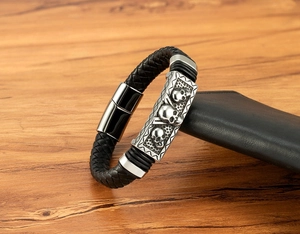 Macro shot of men's leather bracelet showing three skull charms and magnetic clasp