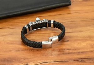 Close-up of black braided leather bracelet with silver brushed metal magnetic clasp on wood
