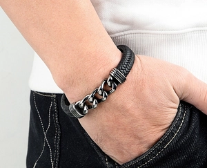 Detail eines Herrenarmbands aus geflochtenem schwarzem Leder und silberner Edelstahlkette