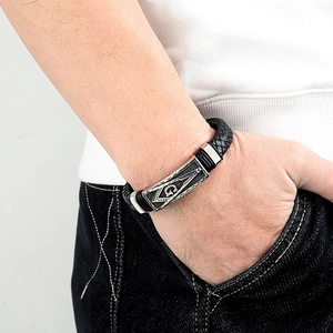 Vue macro du bracelet en cuir tressé noir avec emblème maçonnique argenté et lettre G