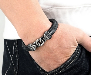 Detailed close-up of men's black braided leather bracelet with vintage metal magnetic clasp