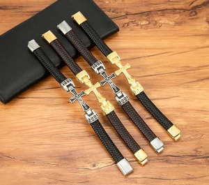 Detail von geflochtenen Lederarmbändern mit Kreuzanhängern auf Holzoberfläche
