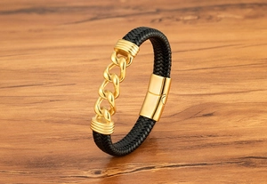Nahaufnahme eines schwarzen Lederarmbands mit goldenen Gliedern und Magnetverschluss