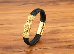 Detail of black woven leather bracelet for men with gold magnetic clasp and floral carvings