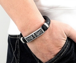 Close-up of leather men's bracelet with silver skull and wings stainless steel charm