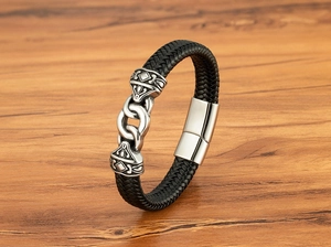 Close-up of woven black leather bracelet with vintage engraved metal magnetic clasp