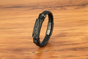Vue macro du symbole G maçonnique sur la plaque en métal du bracelet en cuir tressé noir