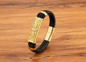 Detailed macro view of the golden skull with wings charm on a black leather bracelet