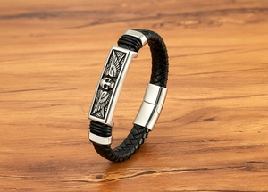 Macro shot of skull and wings relief on black braided leather bracelet with steel magnetic clasp