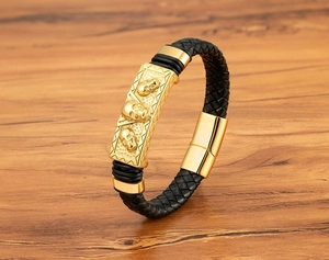 Close-up of golden skull charms on black braided leather bracelet with magnetic clasp