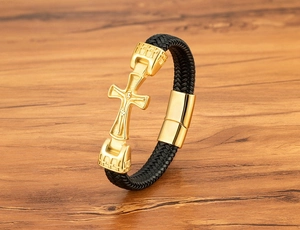 Detailansicht des goldenen Metallkreuzes auf dem schwarzen Lederarmband