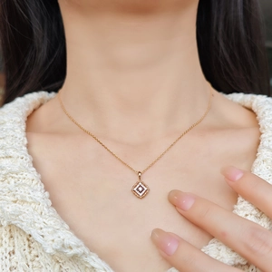 Primo piano di una collana con ciondolo geometrico dorato e cristalli indossata da una modella