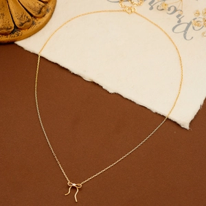Detail van de gouden strik hanger ketting met fonkelende steen en fijne kwastjes