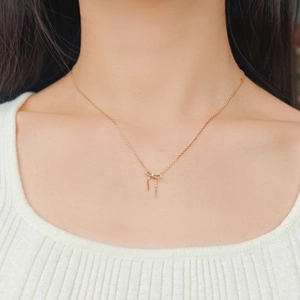 Detailopname van een gouden ketting met strik hanger en kwastjes bij de halslijn