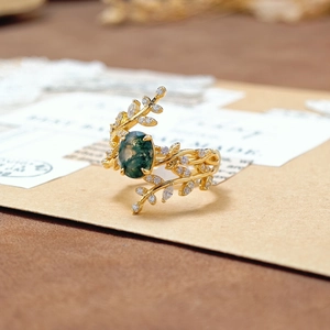 Detail van mosagaat ring met gouden bladontwerp en witte zirkoonaccenten op kaart