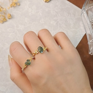 Macro-opname van hart- en ovale mosagaat ringen met vintage gouden takontwerp