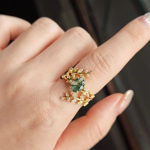 Detail van natuurlijke mosagaat ring met bladpatronen en fonkelende diamanten op hand