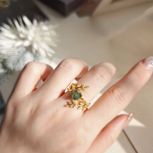 Detailopname van hartvormige mosagaat ring aan hand met wijnstok- en bladdiamantdetails