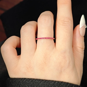 Macro shot of thin rose gold band ring with red ruby stones worn on a finger