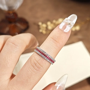 Detailed view of layered S925 silver and gold-plated rings with red and white gemstones