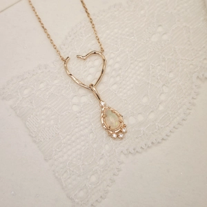 Detail der roségoldenen Herz-Halskette mit opalisierendem Tropfen auf Spitze