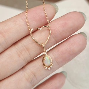 Makroaufnahme des Herzanhängers mit Aststruktur, Tropfen-Opal und Goldkette