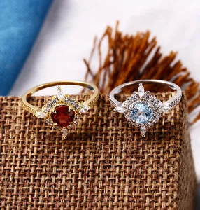 Close-up of 925 silver rings with red and sky blue zircon stones on linen background
