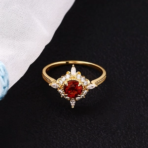 Macro detail of gold vintage ring with red center stone and white marquise zircons
