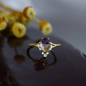 Gros plan d'une bague en argent doré avec améthyste en poire et détails en diamants