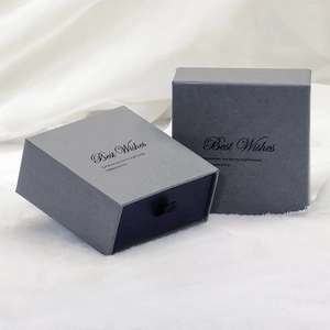 Détail d'un écrin à bijoux gris avec texte Best Wishes sur un fond de tissu blanc doux
