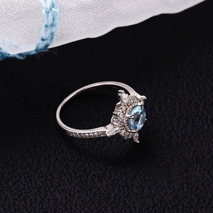 Macro detail of sunflower ring with blue center stone and sparkling zircons on silver band