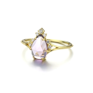 Détail d'une bague dorée S925 avec améthyste poire et sertissage de pierres en couronne