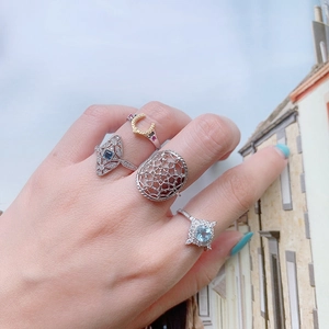 Detailed view of silver rings set with blue and pink gemstones on a hand model