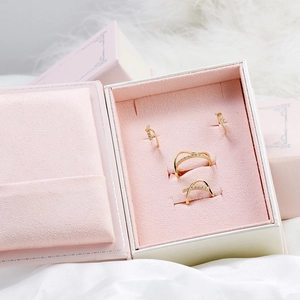 Vue détaillée de bagues et boucles d'oreilles en or dans un écrin de bijoux en velours rose