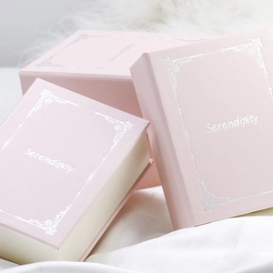 Détail de coffrets cadeaux bijoux roses en forme de livre avec gravure Serendipity