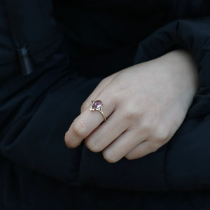 Vue macro d'une bague dorée élégante avec pierre violette en forme de goutte